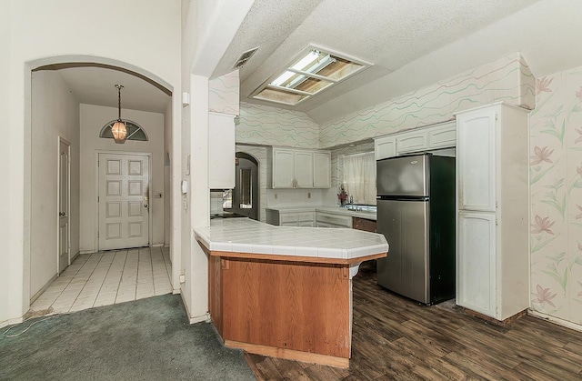 7543 N Spalding Ave, Fresno, CA 93720 - kitchen featuring freestanding refrigerator, arched walkways, a peninsula, lofted ceiling, and tile countertops