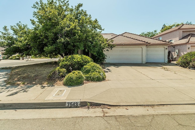 7543 N Spalding Ave, Fresno, CA 93720 - view of front facade with a garage, concrete driveway, a tiled roof, and stucco siding