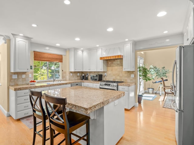 811 E Country View Cir, Fresno, CA 93730 - kitchen with stainless steel appliances, light countertops, white cabinets, a center island, and light wood finished floors