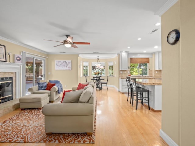 811 E Country View Cir, Fresno, CA 93730 - living room with light wood finished floors, a ceiling fan, a tiled fireplace, ornamental molding, and recessed lighting