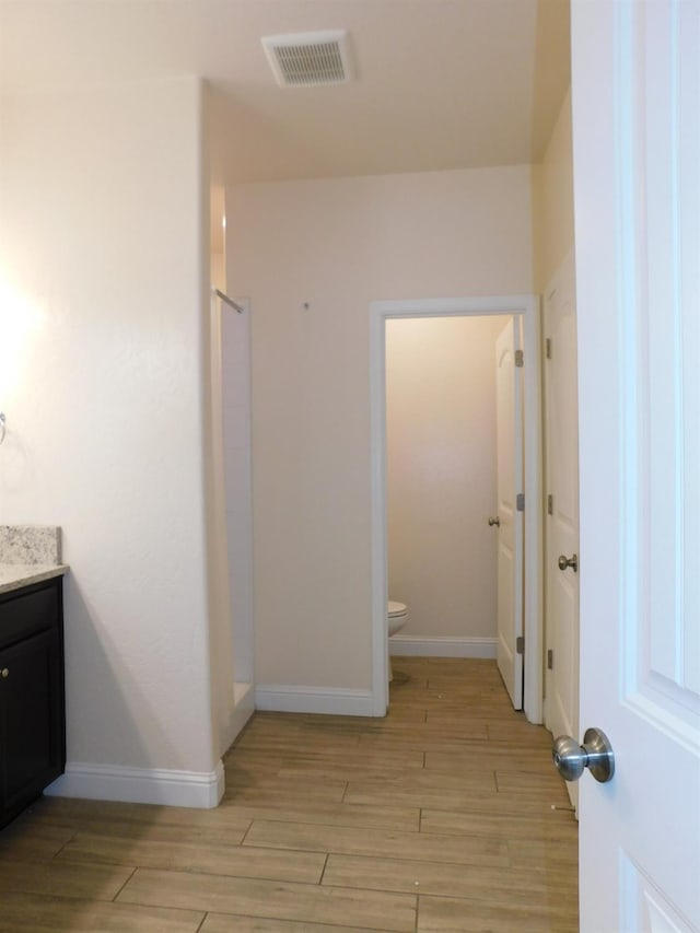 5875 E Pitt Ave, Fresno, CA 93727 - bathroom with wood finished floors, vanity, toilet, a walk in shower, and baseboards