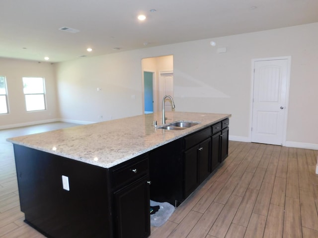 5875 E Pitt Ave, Fresno, CA 93727 - kitchen with a sink, dark cabinetry, light wood-style flooring, light stone counters, and baseboards