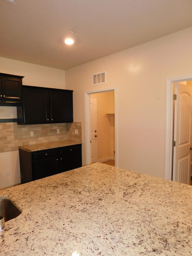 5875 E Pitt Ave, Fresno, CA 93727 - kitchen featuring tasteful backsplash, light stone countertops, and dark cabinetry