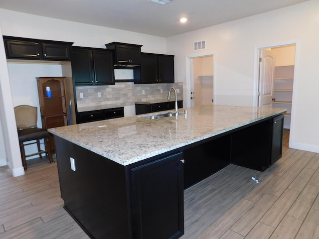 5875 E Pitt Ave, Fresno, CA 93727 - kitchen with a sink, dark cabinetry, light wood-style floors, a large island with sink, and recessed lighting