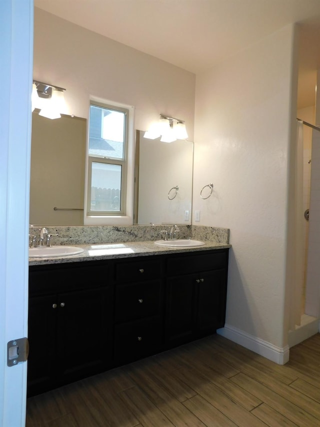 5875 E Pitt Ave, Fresno, CA 93727 - full bathroom featuring double vanity, wood finished floors, a walk in shower, and baseboards