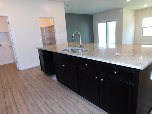 5875 E Pitt Ave, Fresno, CA 93727 - kitchen featuring a sink, dark cabinetry, light wood finished floors, and light stone countertops