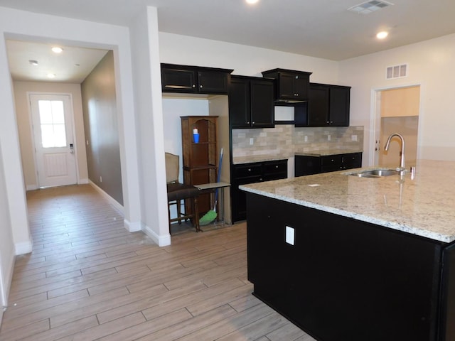 5875 E Pitt Ave, Fresno, CA 93727 - kitchen featuring a sink, dark cabinetry, light wood-style floors, decorative backsplash, and baseboards
