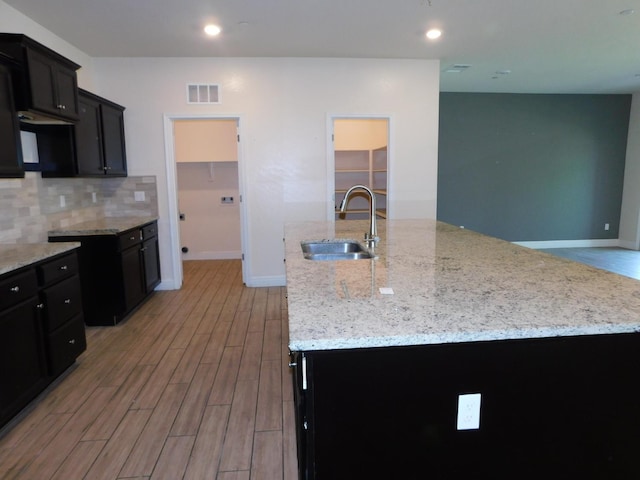 5875 E Pitt Ave, Fresno, CA 93727 - kitchen with a sink, light stone countertops, light wood-type flooring, a kitchen island with sink, and baseboards