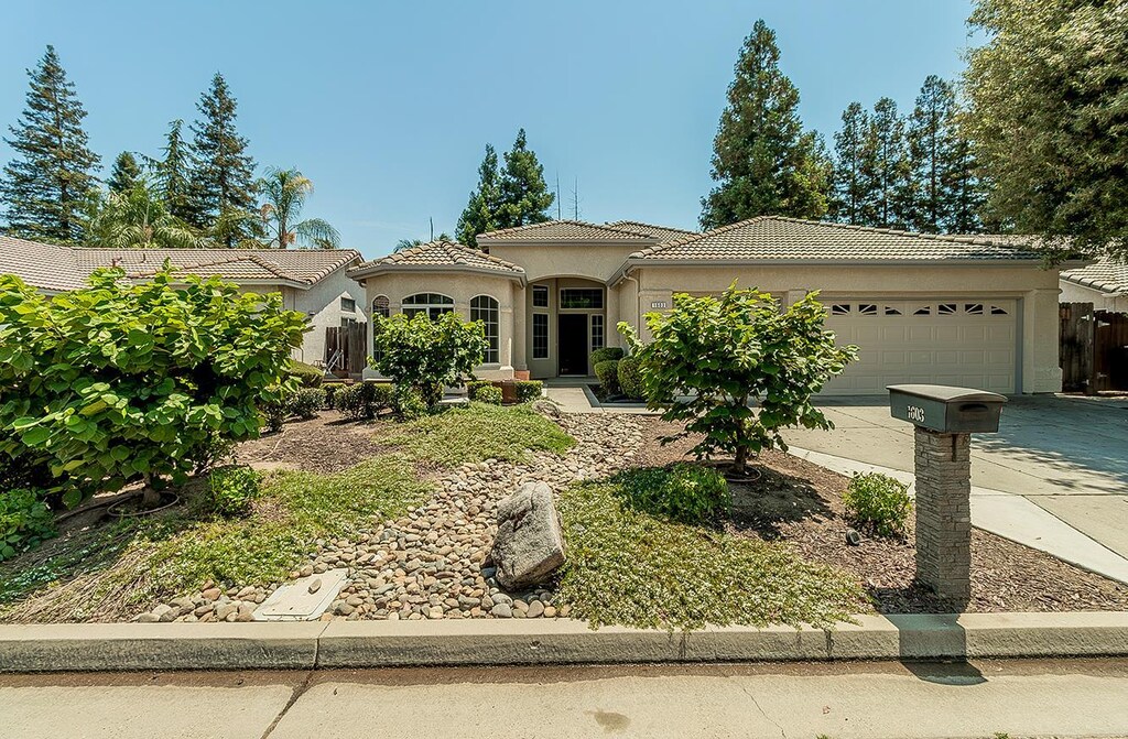 1603 E Waterford Ave, Fresno, CA 93720 - mediterranean / spanish-style house featuring an attached garage, a tiled roof, driveway, and stucco siding