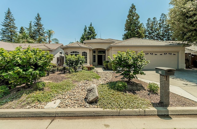 1603 E Waterford Ave, Fresno, CA 93720 - mediterranean / spanish-style house featuring an attached garage, a tiled roof, driveway, and stucco siding