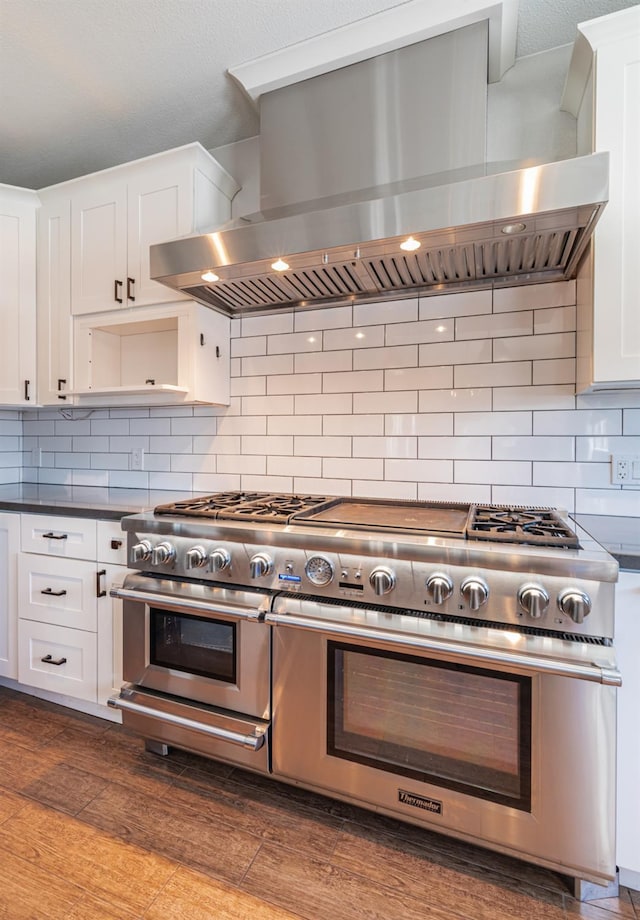 697 E Omaha Ave, Fresno, CA 93720 - kitchen with wall chimney exhaust hood, double oven range, white cabinets, decorative backsplash, and dark countertops
