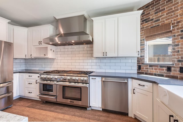 697 E Omaha Ave, Fresno, CA 93720 - kitchen featuring wall chimney range hood, stainless steel appliances, wood finished floors, white cabinets, and dark countertops