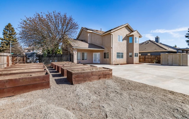 697 E Omaha Ave, Fresno, CA 93720 - back of house with a patio area, a fenced backyard, a garden, stucco siding, and roof mounted solar panels