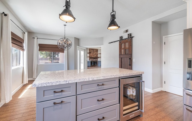 697 E Omaha Ave, Fresno, CA 93720 - kitchen with gray cabinetry, wine cooler, light wood finished floors, and a barn door