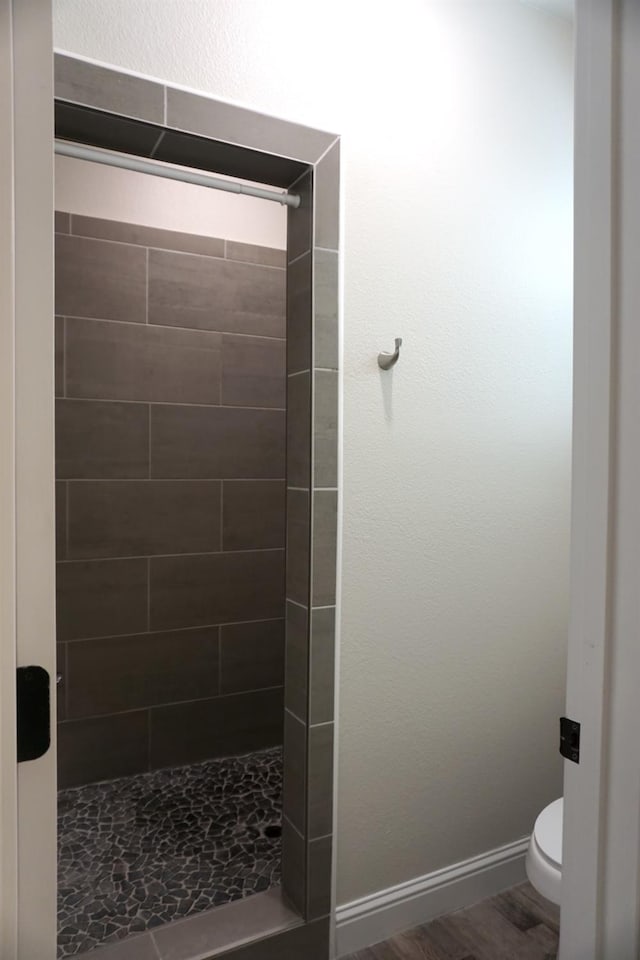 29030 Yosemite Springs Pkwy, Coarsegold, CA 93614 - bathroom featuring a tile shower, toilet, baseboards, and wood finished floors