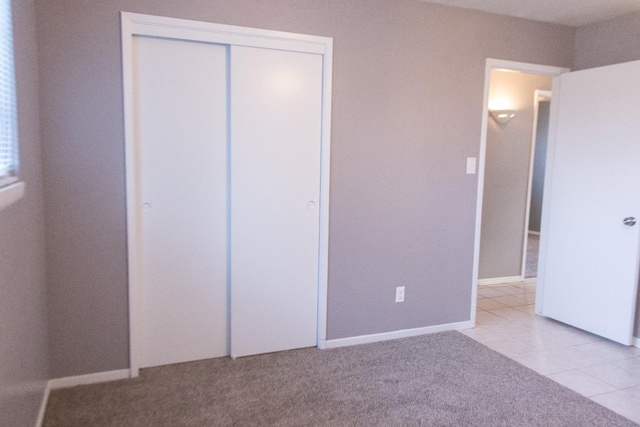 3870 N Fordham Ave, Fresno, CA 93727 - unfurnished bedroom featuring a closet, light tile patterned flooring, and light carpet
