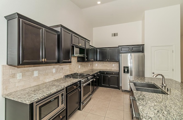 461 S Cascade Way, Madera, CA 93636 - kitchen with appliances with stainless steel finishes, exhaust hood, a towering ceiling, light stone counters, and light tile patterned flooring