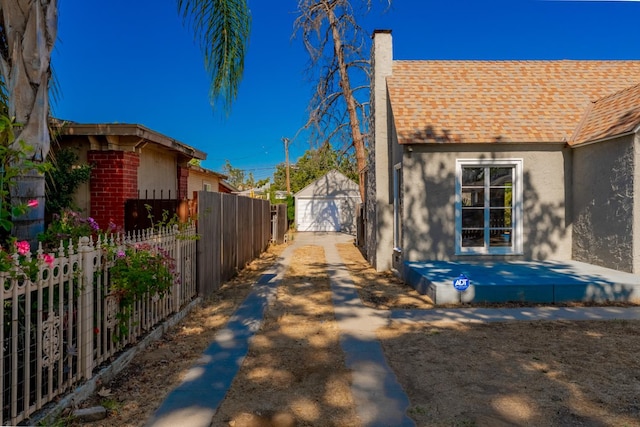 963 N Arthur Ave, Fresno, CA 93728 - view of home's exterior with driveway, a chimney, a shingled roof, a garage, and stucco siding