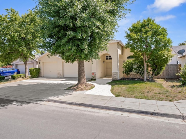 5611 W Carmen Ave, Fresno, CA 93722 - obstructed view of property with concrete driveway, stucco siding, an attached garage, and stone siding
