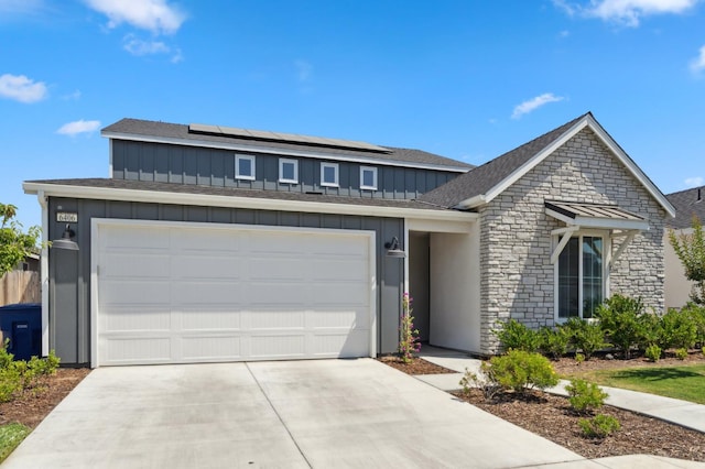 6406 E Giavanna Ave, Fresno, CA 93727 - view of front of property with board and batten siding, concrete driveway, solar panels, stone siding, and roof with shingles