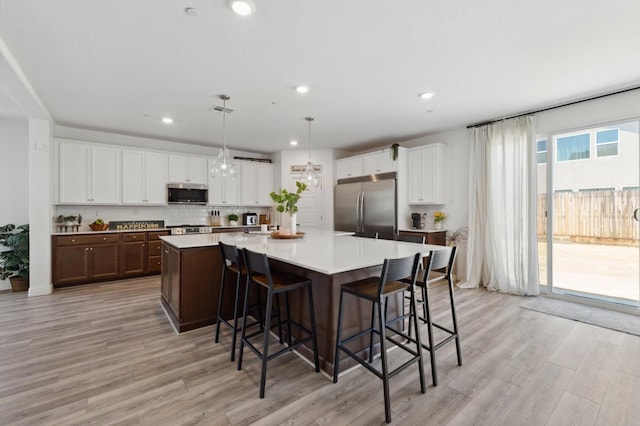 6406 E Giavanna Ave, Fresno, CA 93727 - kitchen with appliances with stainless steel finishes, light wood finished floors, decorative backsplash, a spacious island, and recessed lighting