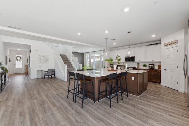 6406 E Giavanna Ave, Fresno, CA 93727 - kitchen with stainless steel microwave, light wood-style flooring, light countertops, a large island, and recessed lighting