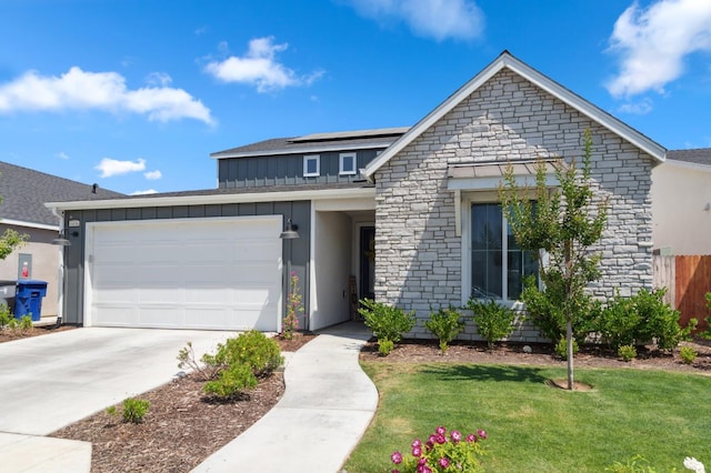 6406 E Giavanna Ave, Fresno, CA 93727 - view of front of house featuring board and batten siding, stone siding, an attached garage, driveway, and solar panels