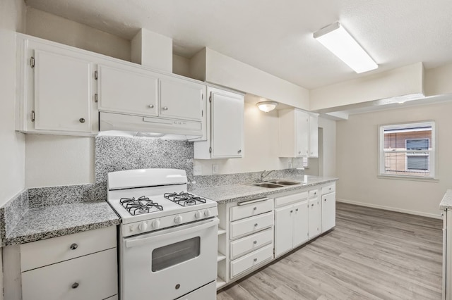 3919 E Butler, Fresno, CA 93702 - kitchen with white range with gas stovetop, under cabinet range hood, light wood-type flooring, white cabinetry, and decorative backsplash