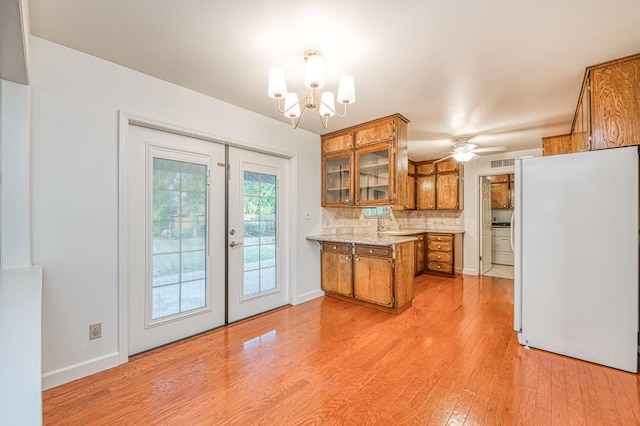 6482 N 5th St, Fresno, CA 93710 - kitchen featuring freestanding refrigerator, brown cabinets, light wood-type flooring, tasteful backsplash, and glass insert cabinets