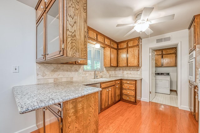 6482 N 5th St, Fresno, CA 93710 - kitchen featuring washer / dryer, brown cabinetry, a peninsula, light wood-style floors, and oven