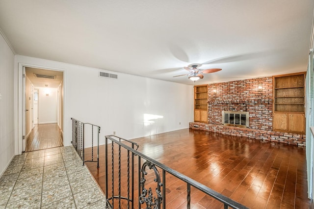 6482 N 5th St, Fresno, CA 93710 - unfurnished living room with ceiling fan, built in features, a fireplace, and wood finished floors