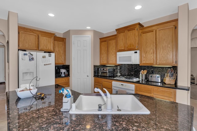 1085 Stanford Ave, Madera, CA 93637 - kitchen with white appliances, recessed lighting, backsplash, arched walkways, and dark stone countertops