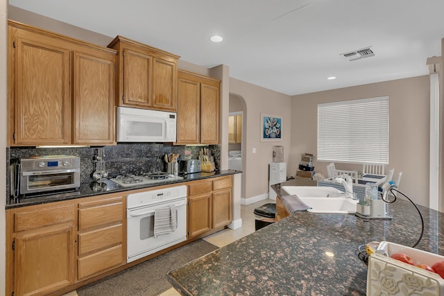 1085 Stanford Ave, Madera, CA 93637 - kitchen with white appliances, arched walkways, tasteful backsplash, recessed lighting, and dark stone counters