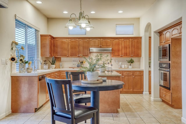 3202 Everglade Ave, Clovis, CA 93619 - kitchen with stainless steel appliances, under cabinet range hood, arched walkways, decorative backsplash, and light tile patterned flooring