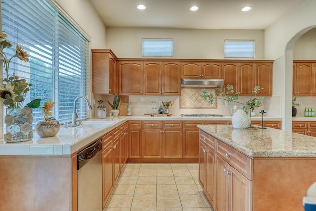 3202 Everglade Ave, Clovis, CA 93619 - kitchen with stainless steel dishwasher, under cabinet range hood, gas stovetop, decorative backsplash, and arched walkways
