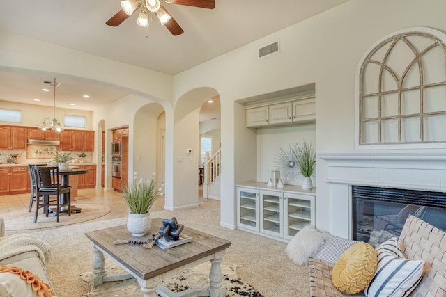 3202 Everglade Ave, Clovis, CA 93619 - living room featuring arched walkways, ceiling fan, stairway, light colored carpet, and a glass covered fireplace