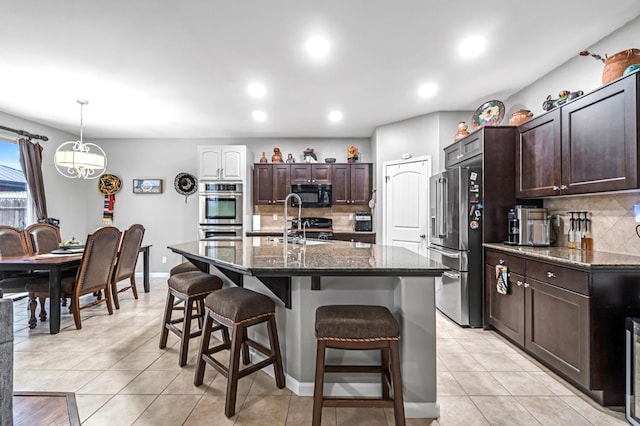 976 Daisy Ct, Dinuba, CA 93618 - kitchen with appliances with stainless steel finishes, decorative backsplash, a kitchen bar, light tile patterned floors, and recessed lighting