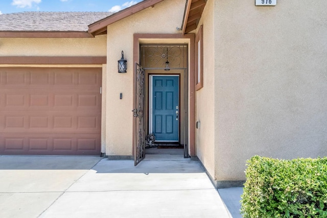 976 Daisy Ct, Dinuba, CA 93618 - property entrance with stucco siding, concrete driveway, and an attached garage