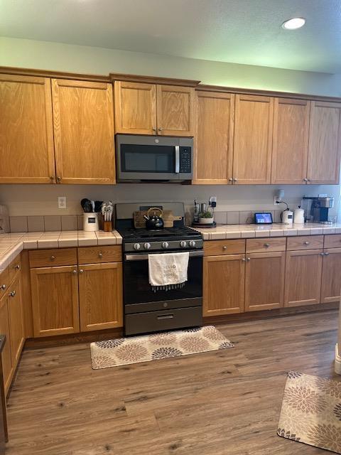 2400 Garda Corte, Chowchilla, CA 93610 - kitchen featuring appliances with stainless steel finishes, tile counters, wood finished floors, and recessed lighting