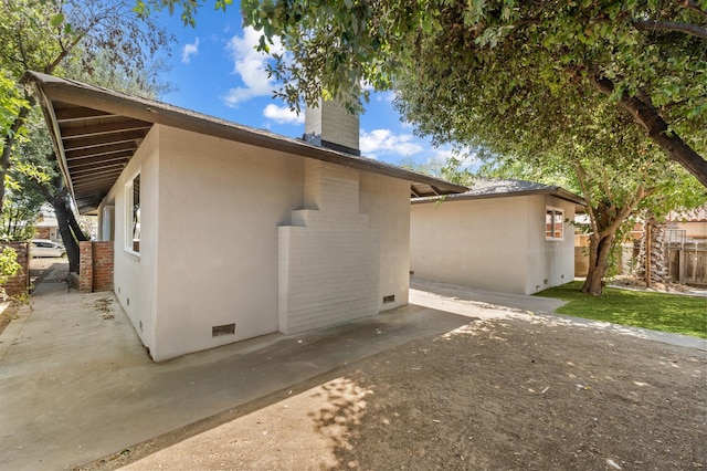 644 W Yale Ave, Fresno, CA 93705 - view of side of home featuring a chimney, a patio, crawl space, stucco siding, and brick siding