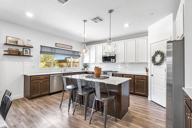 827 Vintage Ave, Clovis, CA 93619 - kitchen with stainless steel appliances, a kitchen bar, light wood finished floors, light countertops, and backsplash