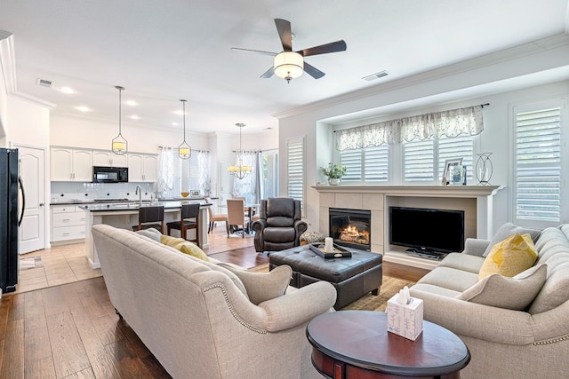 2549 Whiteash Ave, Clovis, CA 93619 - living room featuring ceiling fan, crown molding, a tile fireplace, light wood-style flooring, and recessed lighting