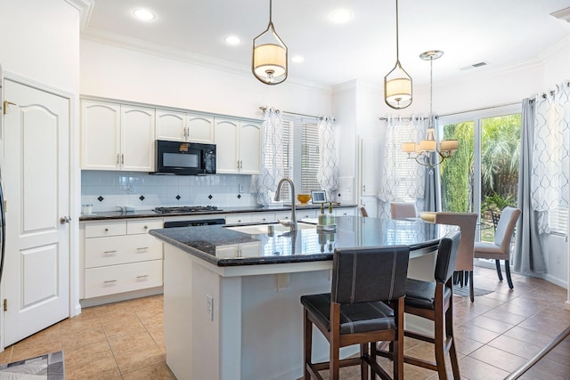 2549 Whiteash Ave, Clovis, CA 93619 - kitchen with black microwave, backsplash, a breakfast bar area, white cabinetry, and crown molding