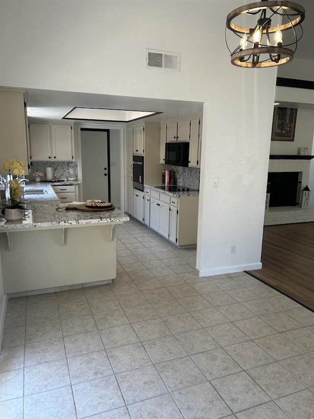 6536 N Tracy Ave, Fresno, CA 93722 - kitchen featuring black appliances, a towering ceiling, a peninsula, decorative backsplash, and a chandelier