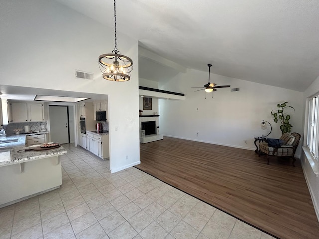 6536 N Tracy Ave, Fresno, CA 93722 - kitchen featuring ceiling fan, high vaulted ceiling, a fireplace with raised hearth, a chandelier, and black appliances