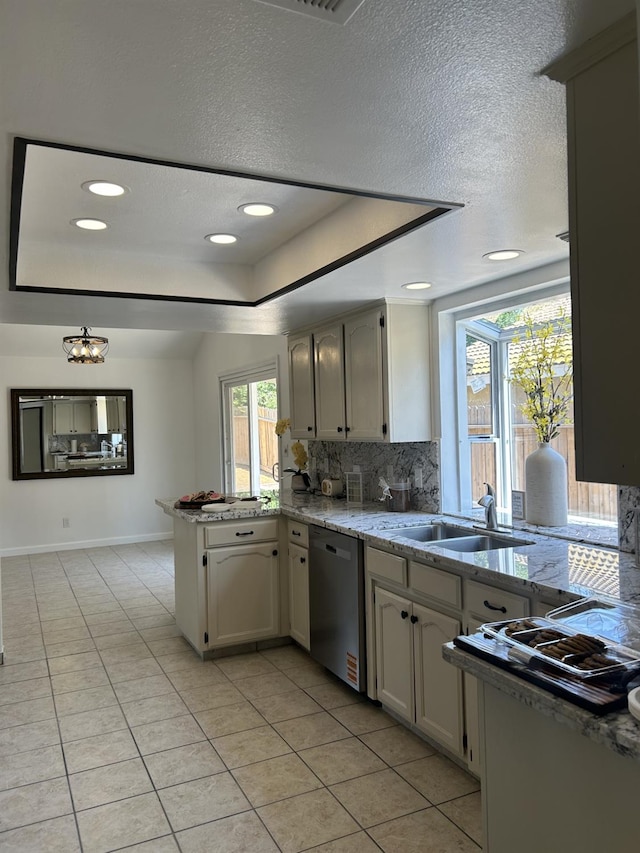 6536 N Tracy Ave, Fresno, CA 93722 - kitchen with stainless steel dishwasher, a peninsula, a tray ceiling, light tile patterned floors, and backsplash