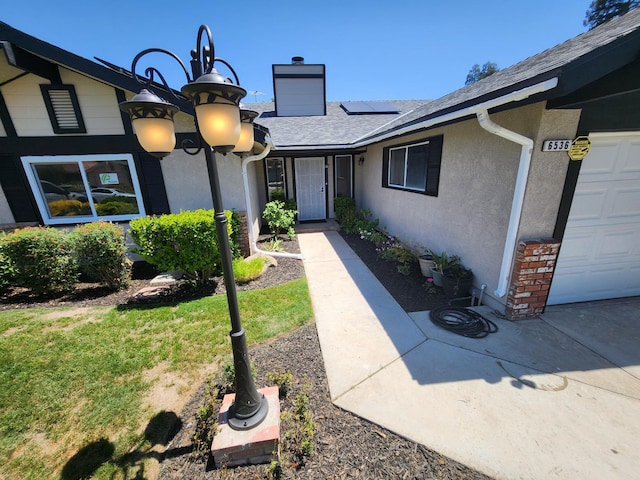 6536 N Tracy Ave, Fresno, CA 93722 - doorway to property with solar panels, a chimney, stucco siding, a shingled roof, and a lawn