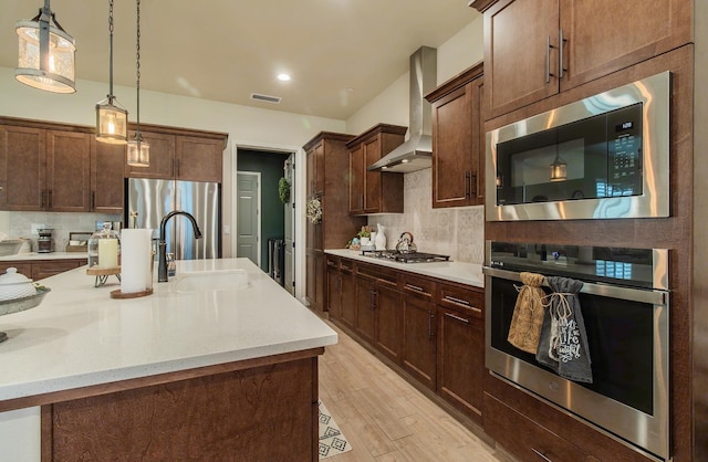 2047 Menlo Ave, Clovis, CA 93611 - kitchen featuring stainless steel appliances, wall chimney range hood, decorative backsplash, pendant lighting, and light wood finished floors