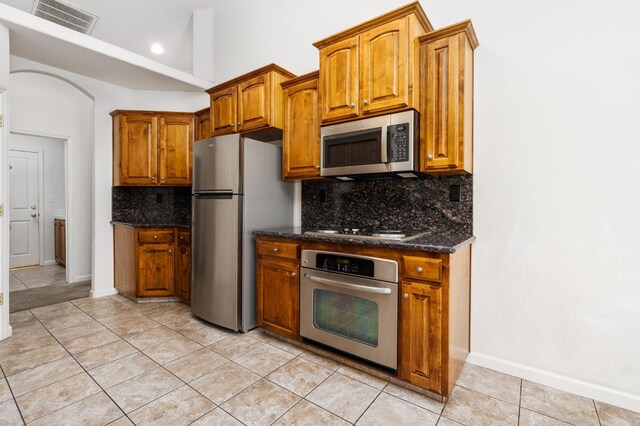 10643 N Tea Party Ln, Fresno, CA 93730 - kitchen with stainless steel appliances, tasteful backsplash, light tile patterned floors, dark stone counters, and recessed lighting