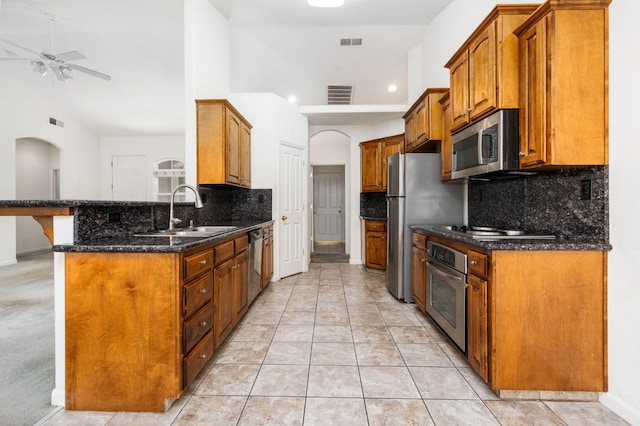 10643 N Tea Party Ln, Fresno, CA 93730 - kitchen with appliances with stainless steel finishes, backsplash, ceiling fan, arched walkways, and brown cabinets